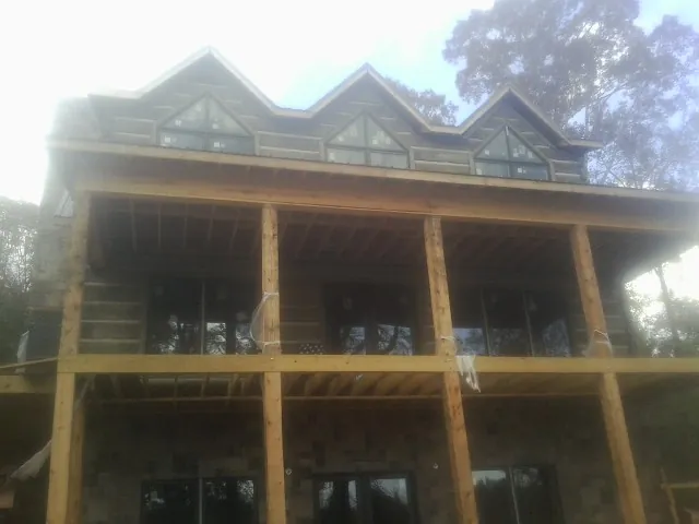 Dormers and porch framing on a large log home under construction — Roof Coating work by our crew in Albion